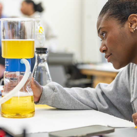 Student looking at a beaker in a chemistry lab