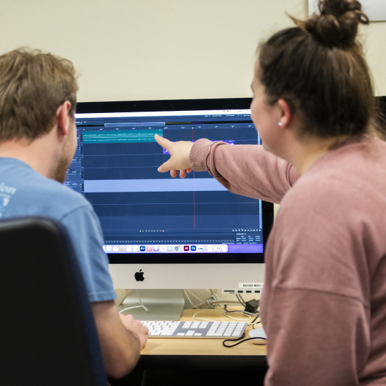 Students pointing at a screen in a computer lab