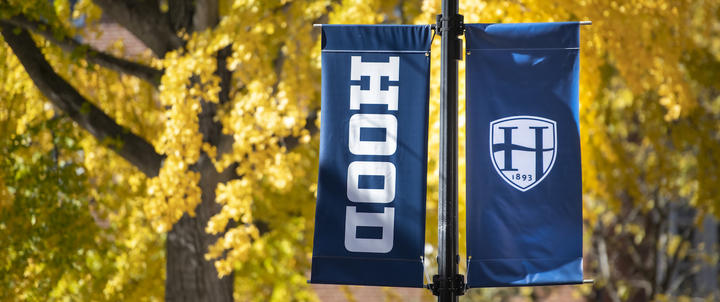 A Hood College banner against fall foliage on campus.