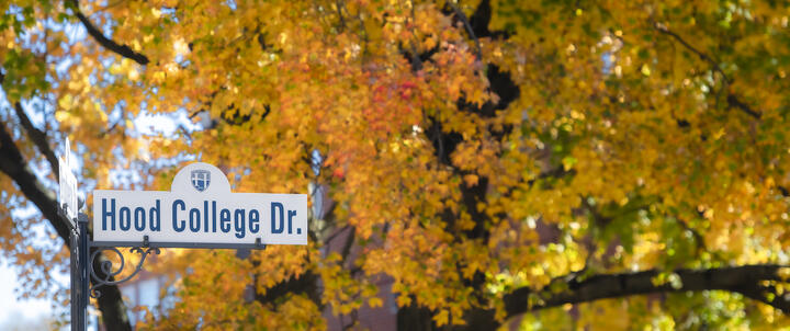 A street sign reading Hood College Drive with fall foliage.